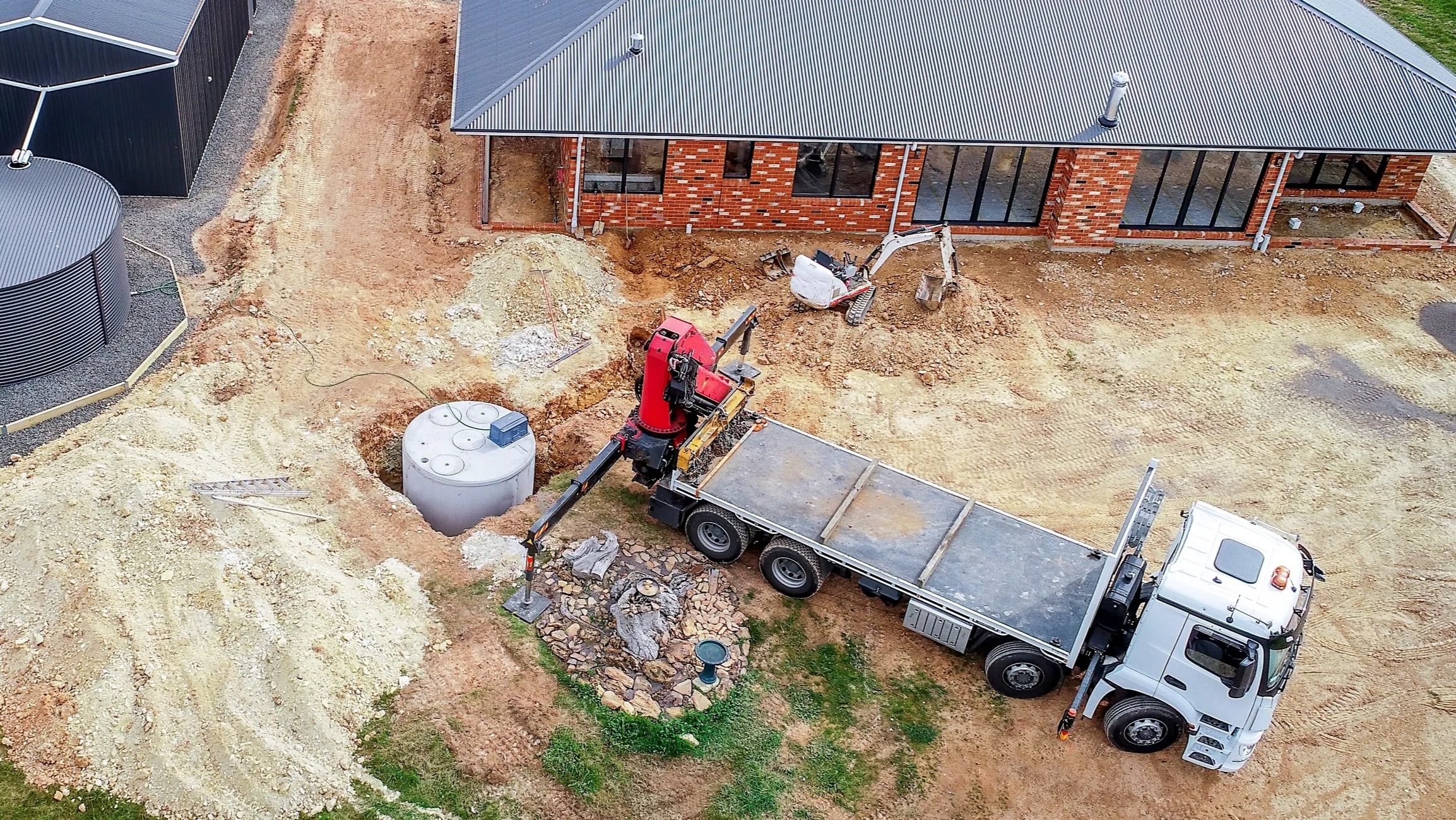 Worker installing drainage pipe in trench